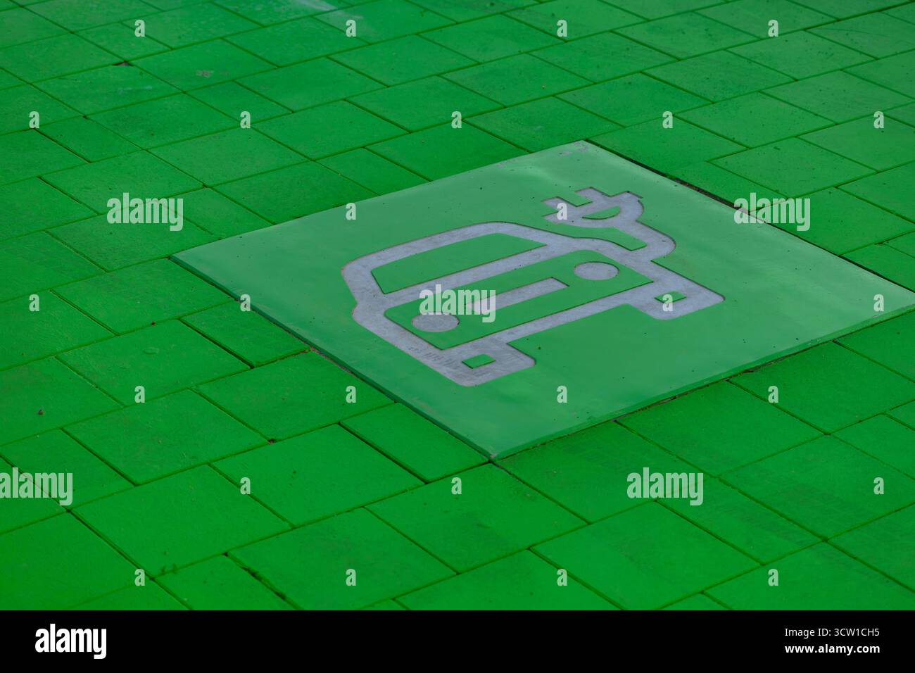 Place de stationnement peinte en vert conçue pour les véhicules électriques avec véhicule électrique et symbole de charge sur le trottoir. Concept de transport durable, ECO mobilit Banque D'Images
