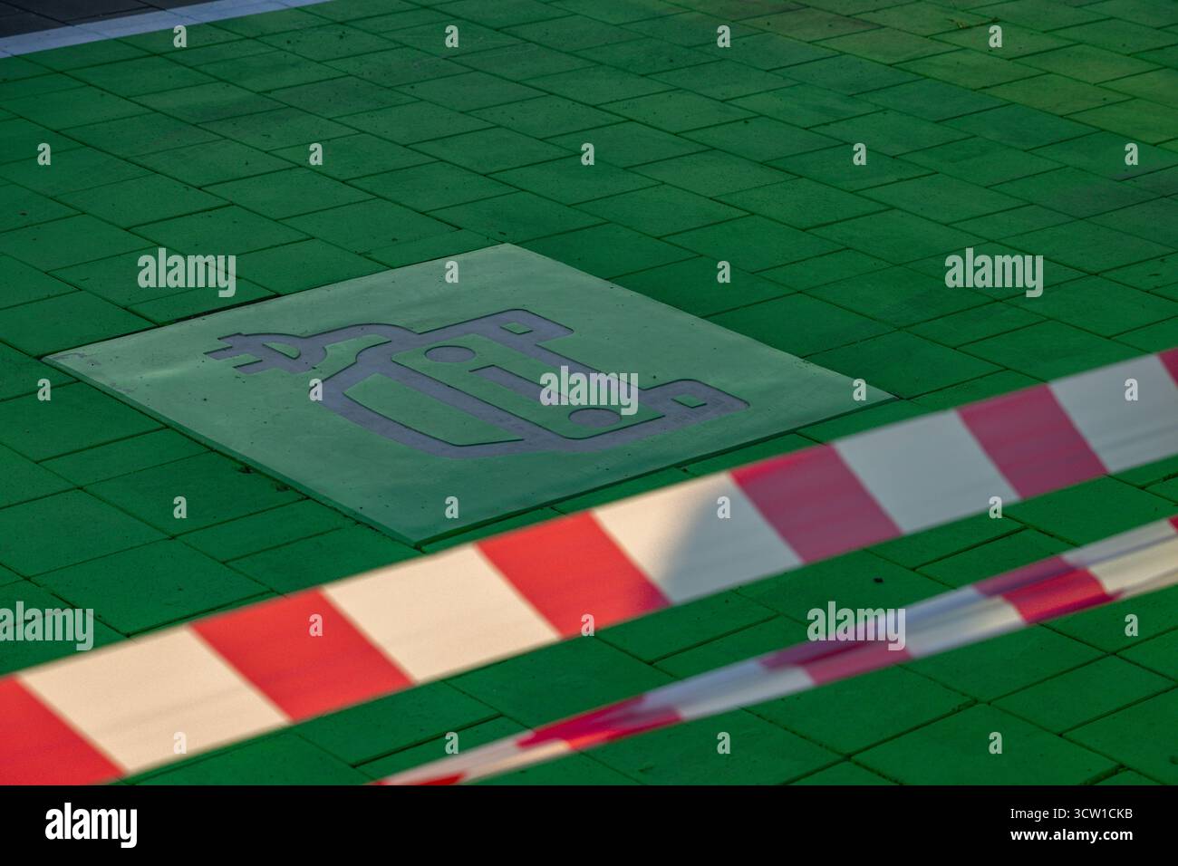 Place de stationnement peinte en vert conçue pour les véhicules électriques avec véhicule électrique et symbole de charge sur le trottoir. Concept de transport durable, ECO mobilit Banque D'Images