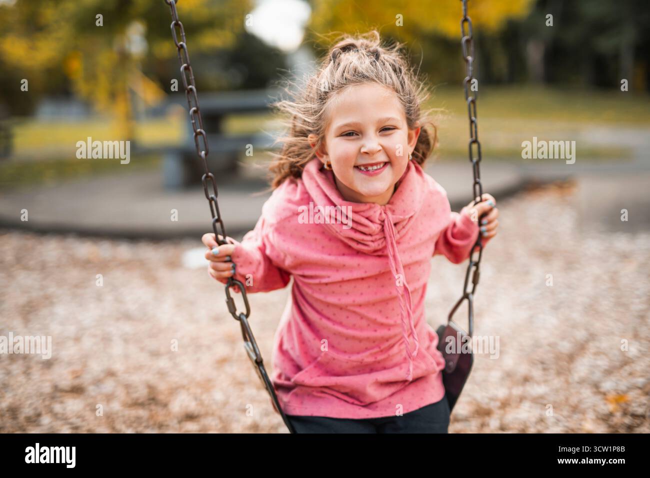 Une petite fille s'amusant sur une aire de jeux dans un parc public le jour d'automne. Banque D'Images