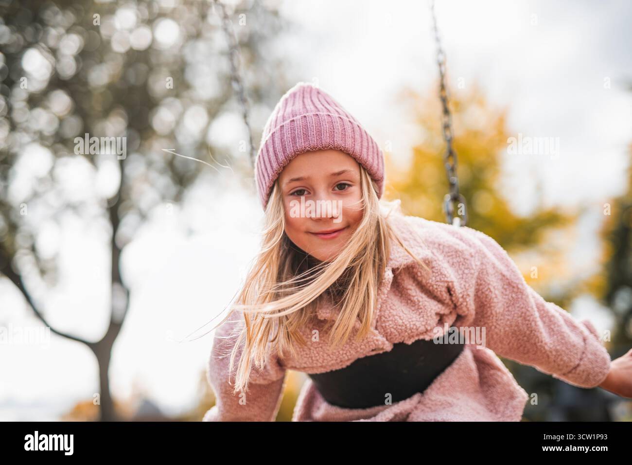 Une petite fille s'amusant sur une aire de jeux dans un parc public le jour d'automne. Banque D'Images