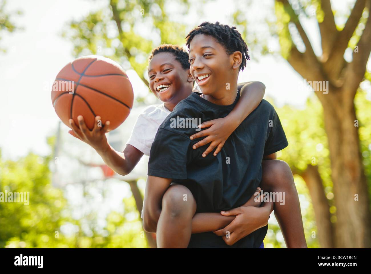 Un portrait de frère jouant avec un ballon de basket dans un parc Banque D'Images
