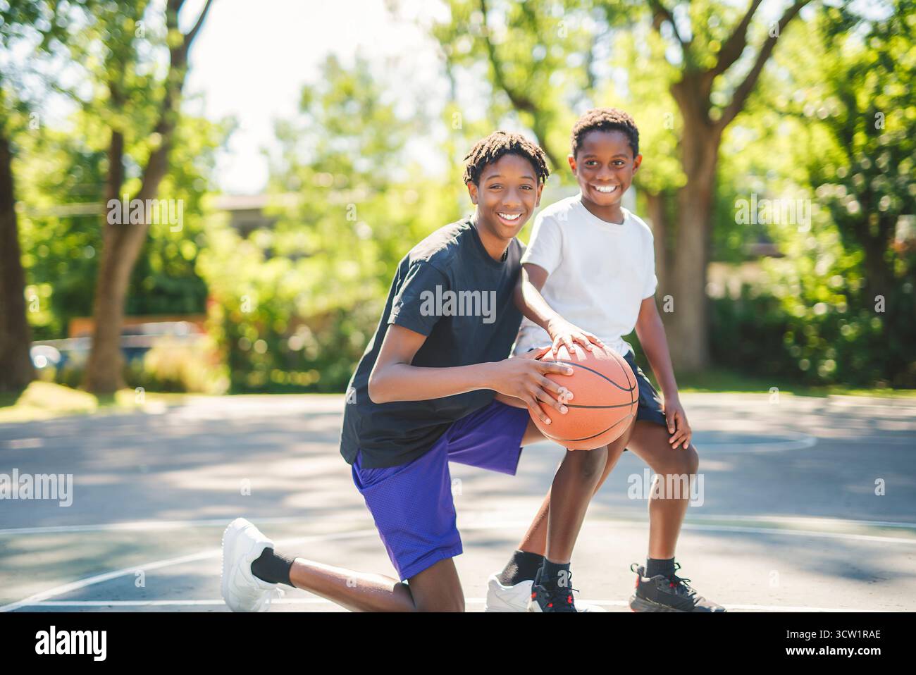 Un portrait de frère jouant avec un ballon de basket dans un parc Banque D'Images