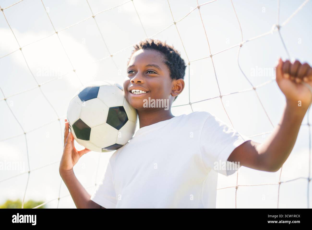 Un jeune enfant jouant au football sur un terrain de jeu Banque D'Images