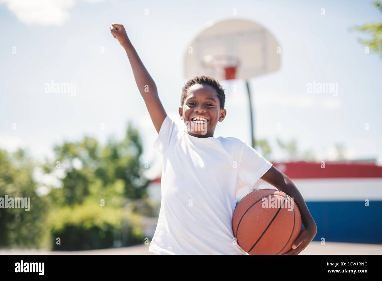 Un portrait d'un garçon jouant avec un basket dans un parc Banque D'Images