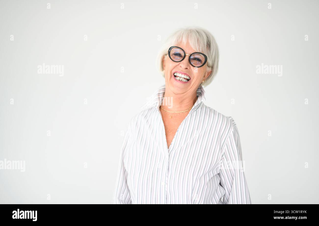 Un portrait de femme âgée dans des lunettes sur fond gris. Banque D'Images