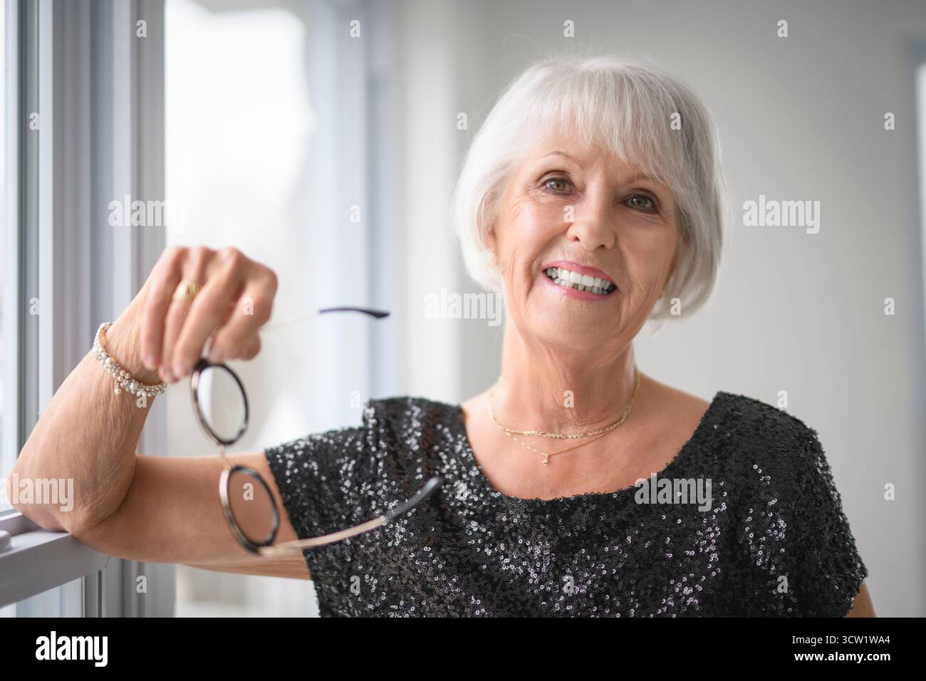 Un portrait de femme âgée dans des lunettes sur fond gris. Banque D'Images