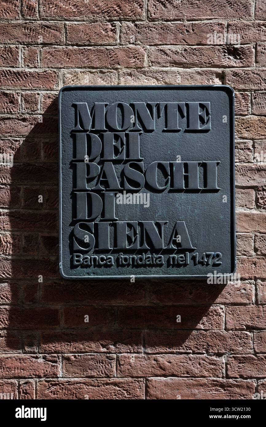 SIENNE, ITALIE - 28 août 2025 : gros plan du panneau métallique de la banque italienne Banca Monte dei Paschi di Siena, sur un fond de mur de pierre Banque D'Images