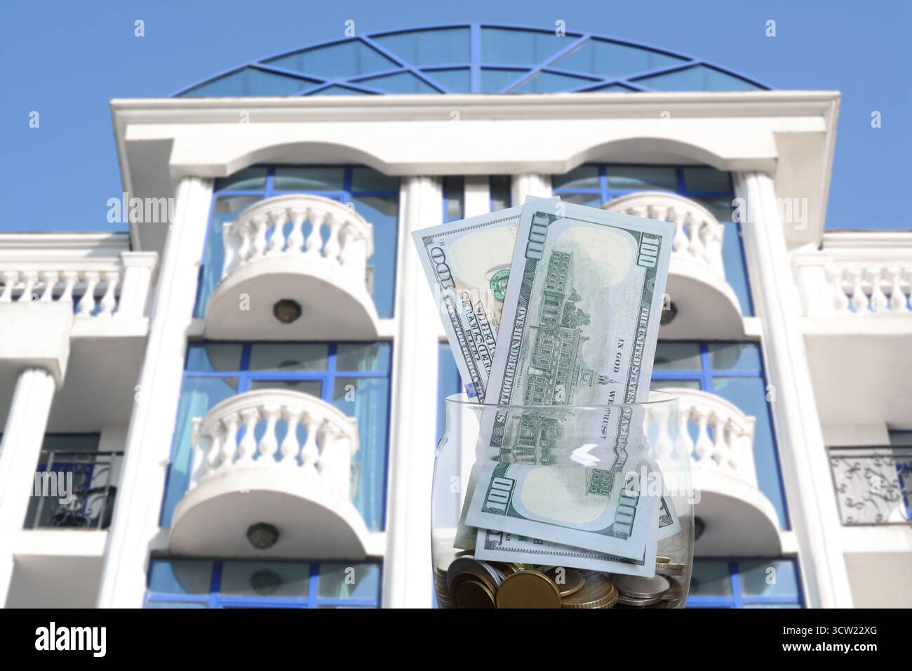 Pot avec des dollars et des pièces contre condominium. Économiser de l'argent pour acheter appartement Banque D'Images