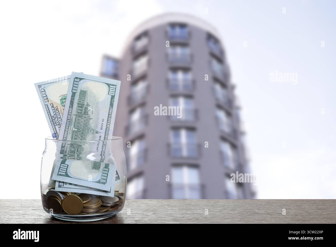 Pot avec des dollars et des pièces contre condominium. Économiser de l'argent pour acheter appartement Banque D'Images