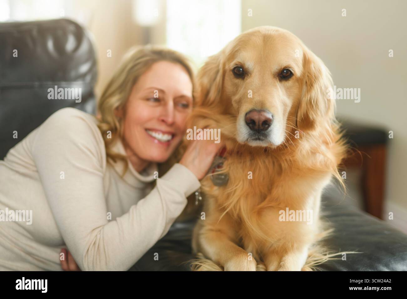 Un portrait de femme avec chien Golden retriever sain à l'intérieur sur le canapé Banque D'Images