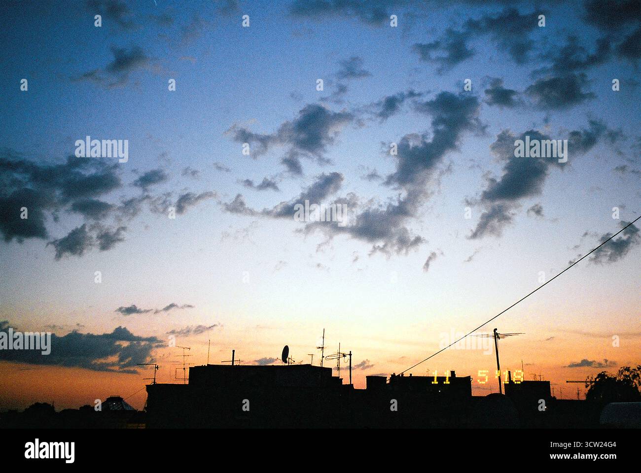 Instantané analogique du coucher de soleil sur des bâtiments silhouettés avec un grand dégradé de ciel et un horodatage jaune à partir de l'empreinte de date intégrée sur l'appareil photo. Banque D'Images