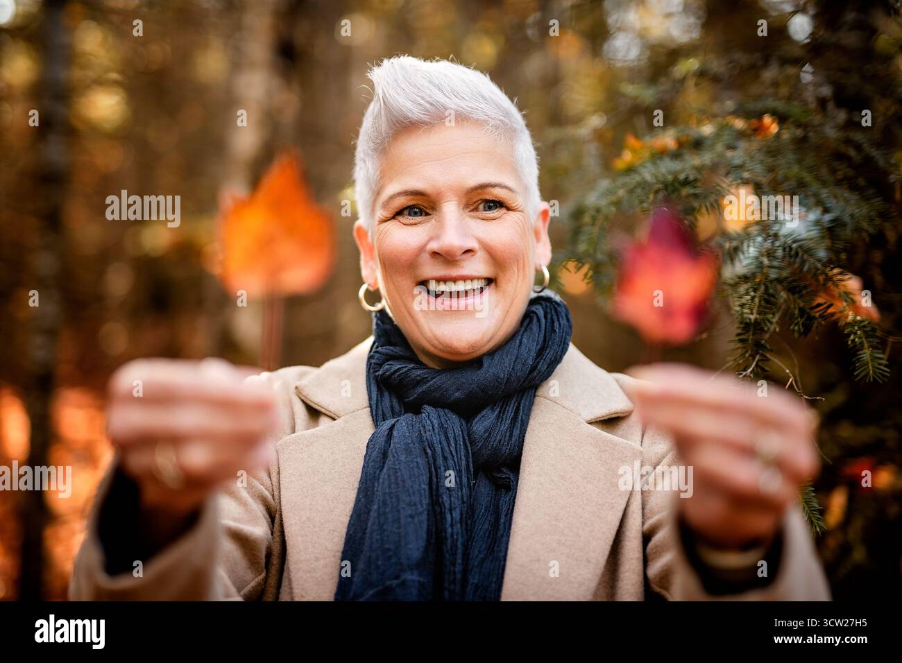 Une femme mature dans la forêt d'automne, vêtue d'une tenue d'automne confortable, réflexion et connexion avec la nature, le bien-être Banque D'Images