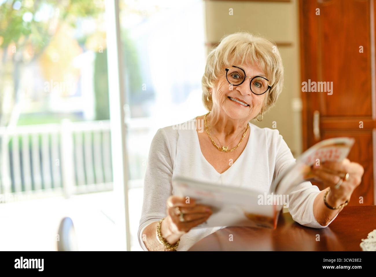 Une femme senior avec magazine at Home Banque D'Images
