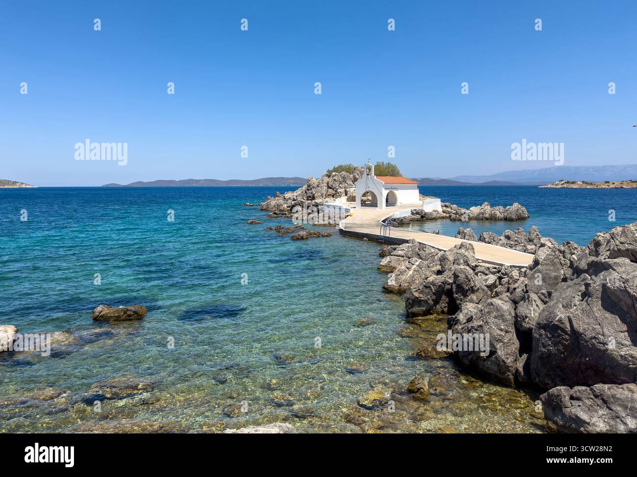 Chios, petite église d'Agios Isidoros, Grèce. Chapelle d'architecture traditionnelle avec toit de tuiles rouges et clocher sur les rochers, journée d'été ensoleillée Banque D'Images