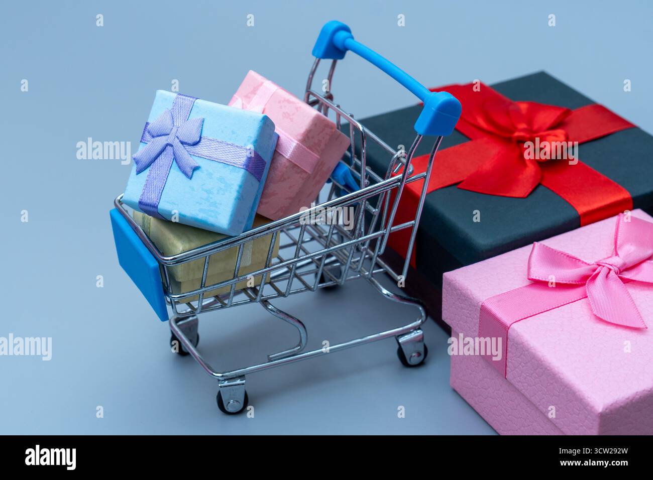 Mini panier rempli de boîtes cadeaux colorées sur fond bleu. Achat en ligne, vente au détail, ventes de vacances et concept d'achat de consommateurs. Banque D'Images
