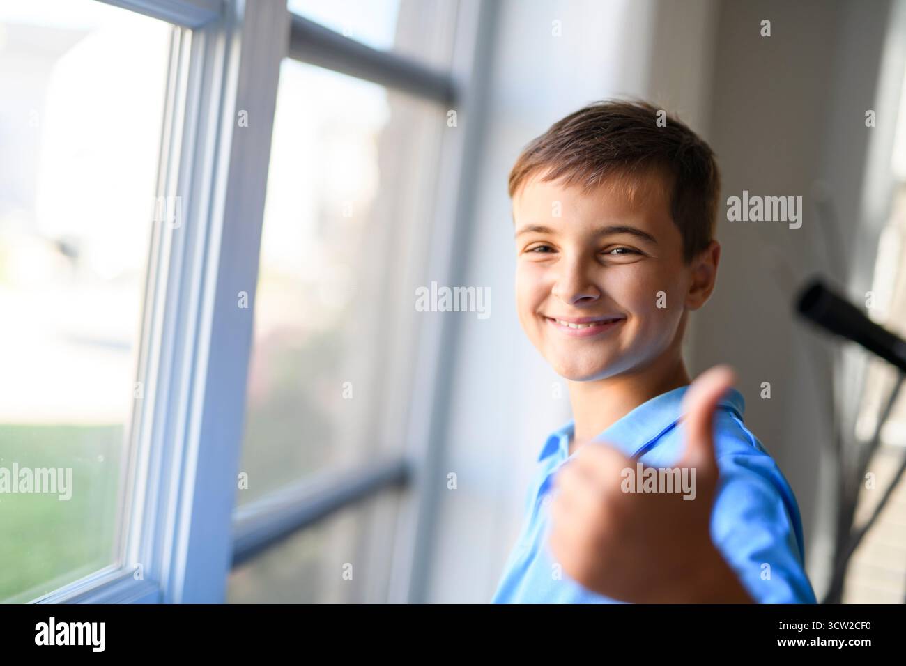 Un jeune adolescent avec près de la fenêtre à la maison Banque D'Images