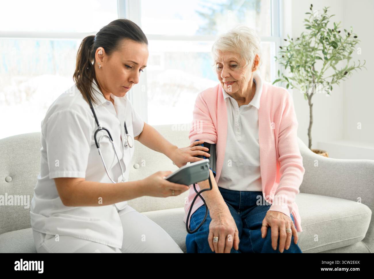 Portrait d'une jeune infirmière médecin avec une patiente âgée à domicile lors d'une consultation Banque D'Images