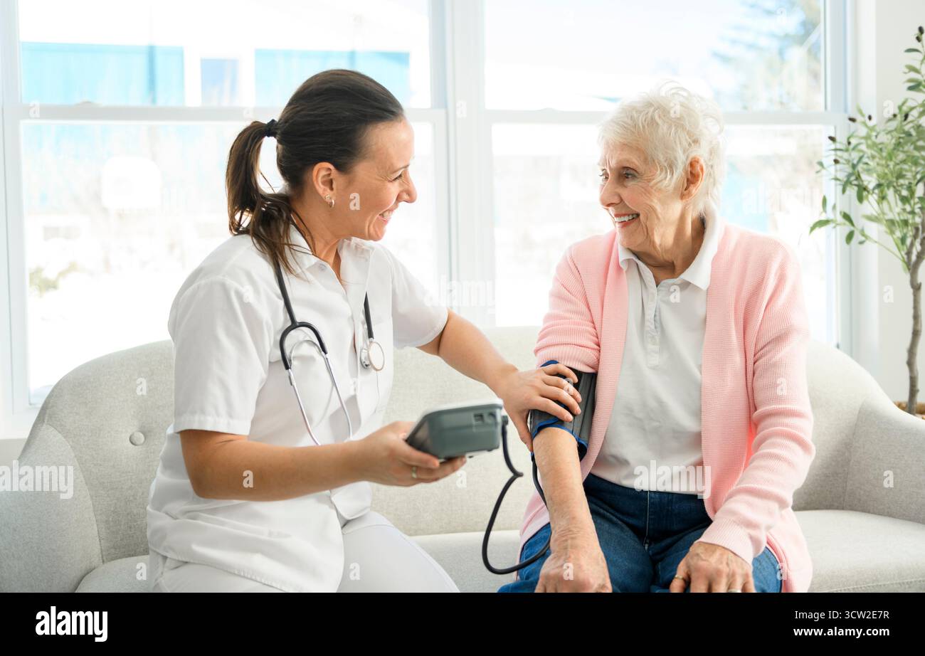 Portrait d'une jeune infirmière médecin avec une patiente âgée à domicile lors d'une consultation Banque D'Images