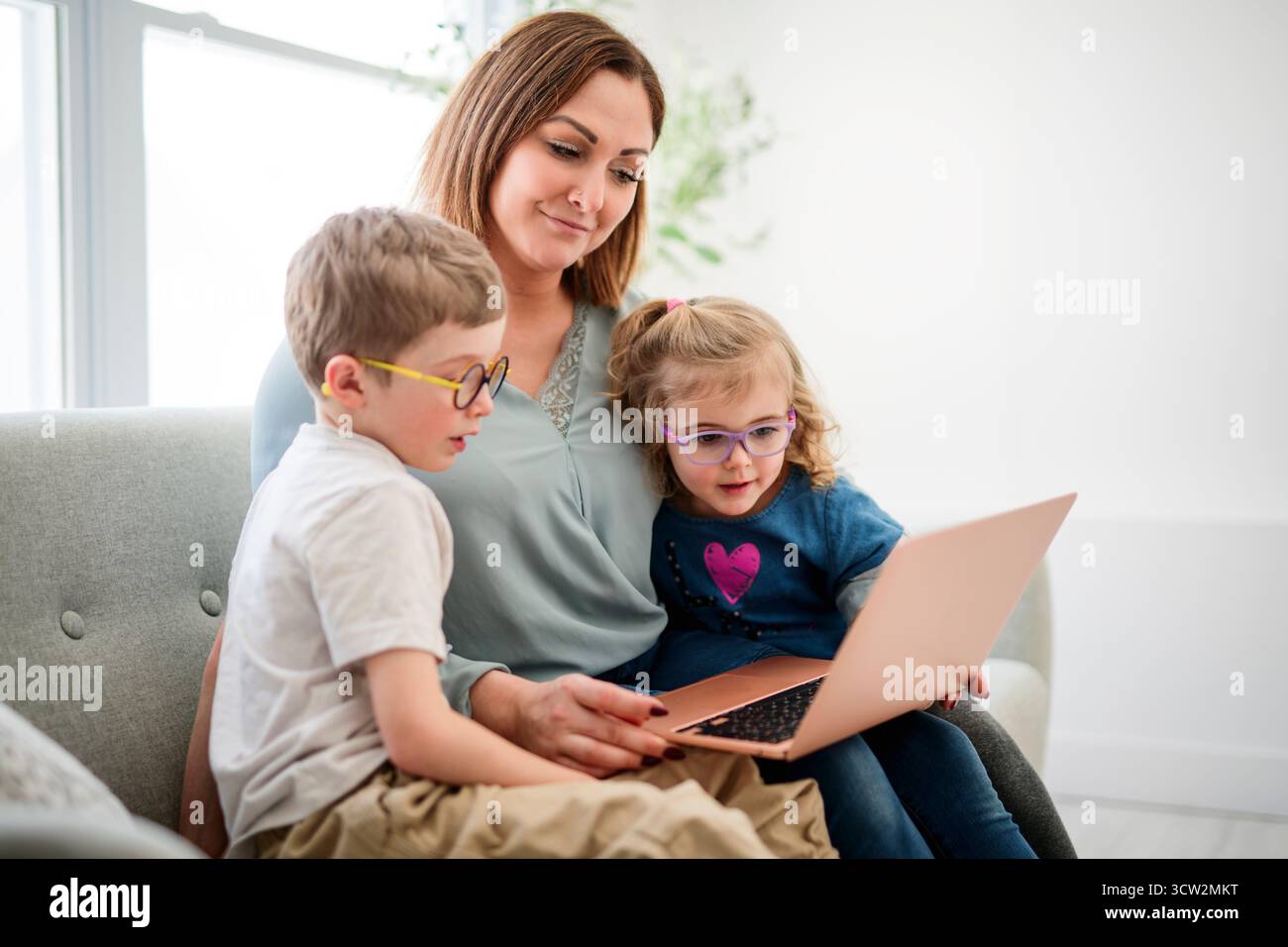 Une mère, ses filles et son fils portrait sont assis sur le canapé avec le chien à la maison Banque D'Images
