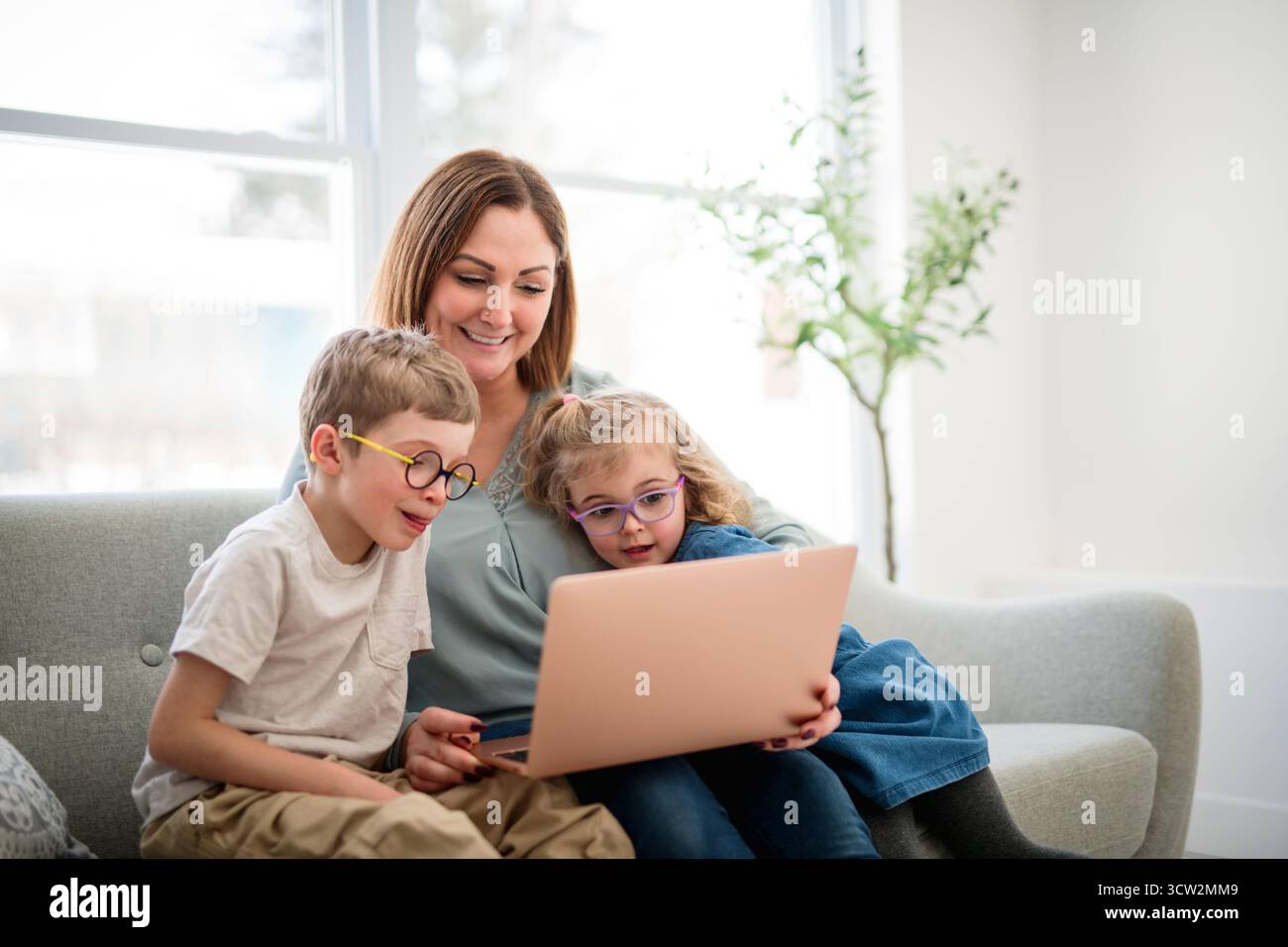 Une mère, ses filles et son fils portrait sont assis sur le canapé avec le chien à la maison Banque D'Images