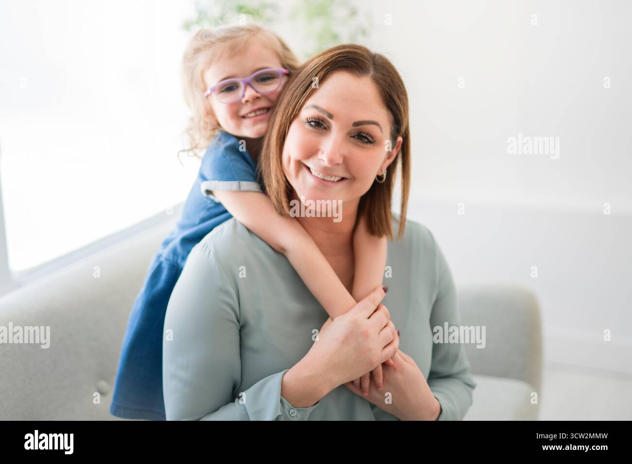 Un portrait d'une fille handicapée souriant à la caméra avec sa mère à la maison Banque D'Images