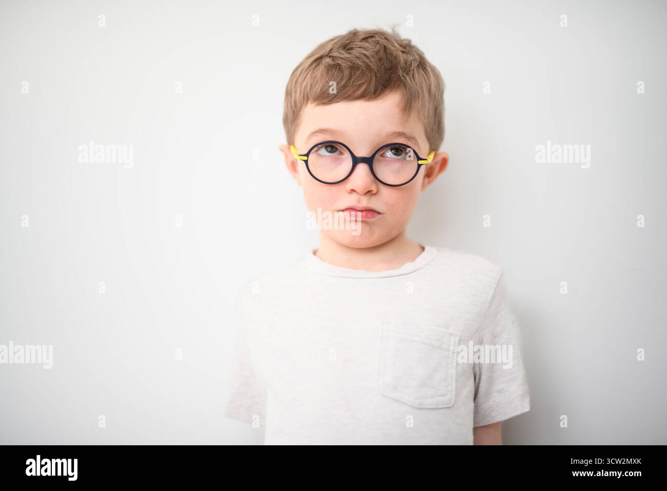 Un portrait de beau petit garçon dans des lunettes isolé sur fond gris Banque D'Images