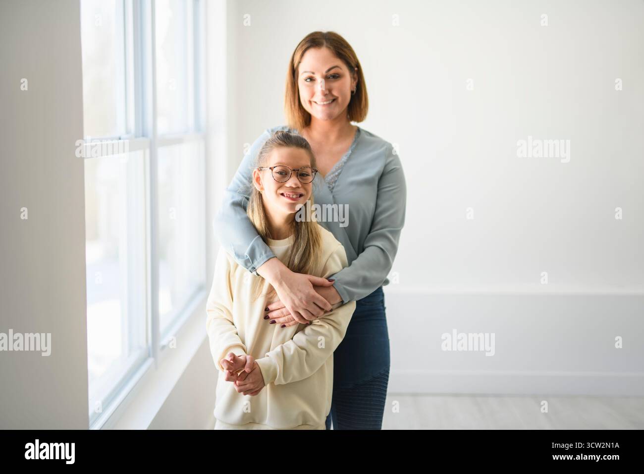 Un portrait d'une fille handicapée souriant à la caméra avec sa mère Banque D'Images