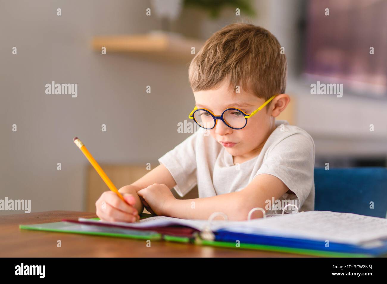 Un concept de devoirs et d'école - garçon étudiant avec l'écriture de livre au cahier à la maison Banque D'Images