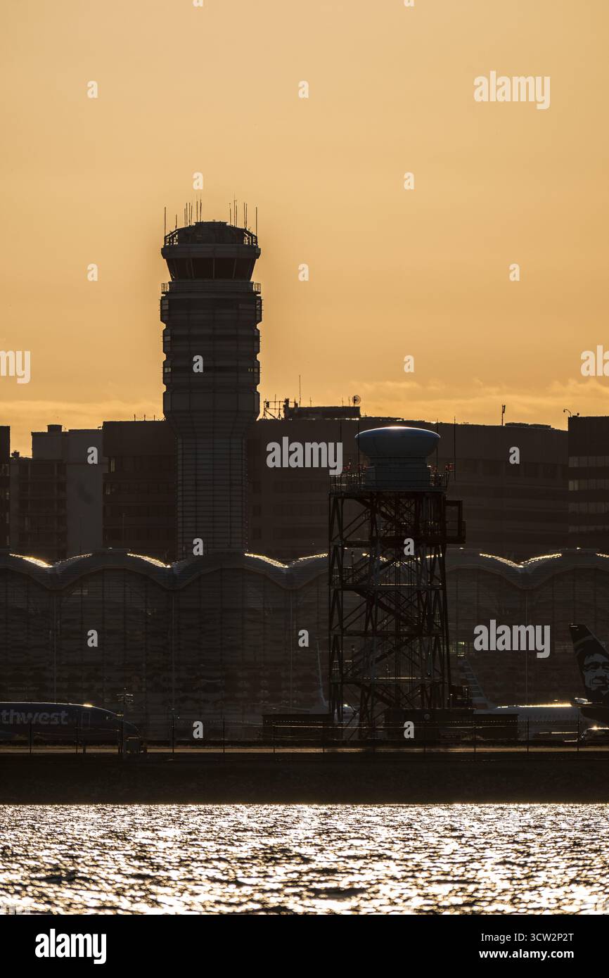 Tour de contrôle de la circulation aérienne de l'aéroport national Reagan à Sunset Washington DC // WASHINGTON DC — la tour de contrôle de la circulation aérienne et le bâtiment terminal de l'aéroport national Ronald Reagan Washington (DCA) sont dessinés contre le soleil couchant. Cette vue est capturée depuis Hains point, un parc de la péninsule dans East Potomac Park, surplombant le fleuve Potomac. L'aéroport national Ronald Reagan de Washington est une plaque tournante de transport majeure pour la région métropolitaine de Washington D.C. desservant principalement les vols intérieurs. L'aéroport est situé à seulement 8 kilomètres au sud du centre-ville de Washington D.C. Banque D'Images