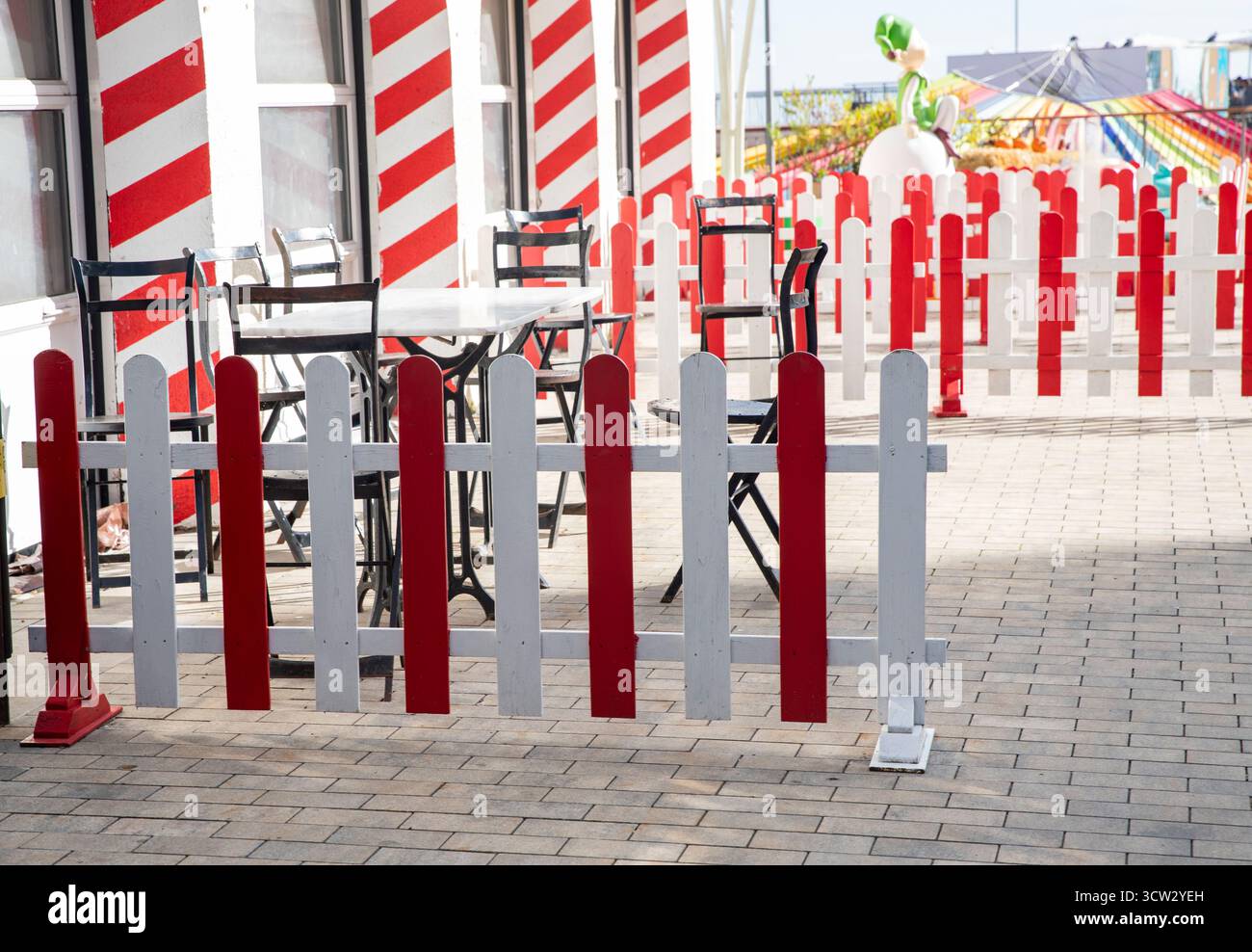 Clôture décorative à rayures rouges et blanches devant les tables et les chaises à l'extérieur. Banque D'Images