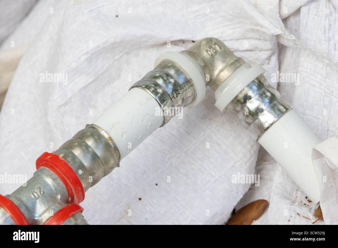 Gros plan des tuyaux d'eau à raccord serré installés par un plombier à l'aide d'un outil de sertissage, montrant le raccordement sécurisé Banque D'Images