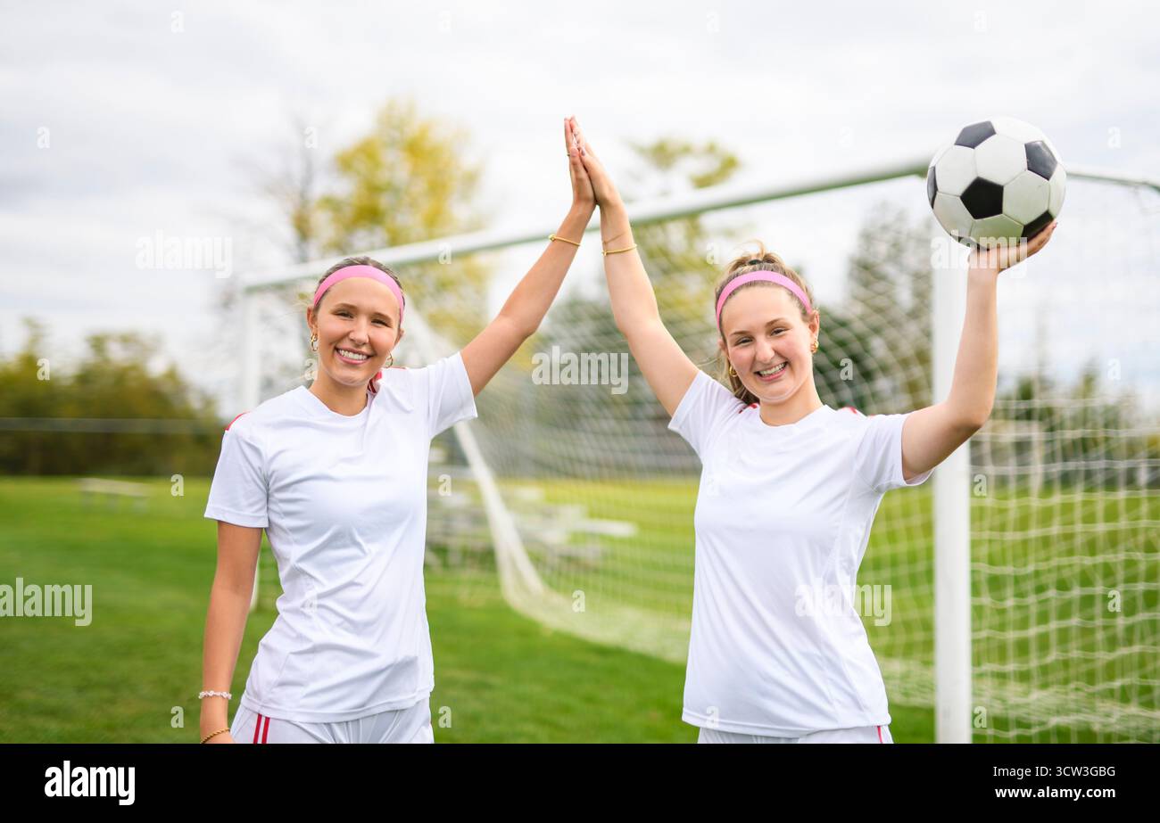 Les deux joueurs de football sont amis avec un ballon de football en uniforme de sport portant en blanc Banque D'Images