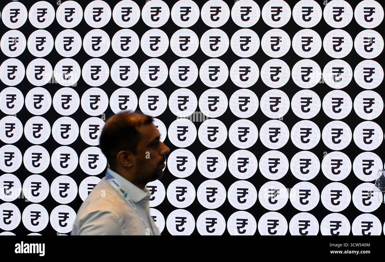 Un homme passe devant le symbole « Roupie » affiché sur un écran LED le dernier jour du sixième Global Fintech Fest (GFF) à Mumbai. L’événement de trois jours qui s’est tenu du 7 au 9 octobre 2025, une plateforme mondiale pour encourager les principaux acteurs des firmes Fintech, qui se sont rassemblés pour partager et échanger des idées, et l’innovation dans les domaines bancaire, financier, de l’intelligence artificielle, des paiements numériques, des startups, et les nouvelles technologies se sont achevées le dernier jour avec le premier ministre indien Narendra Modi et le premier ministre britannique Keir Starmer qui ont pris la parole devant les délégués présents à l’événement. (Photo Ashish Vaishnav/SOPA images/Sipa Banque D'Images
