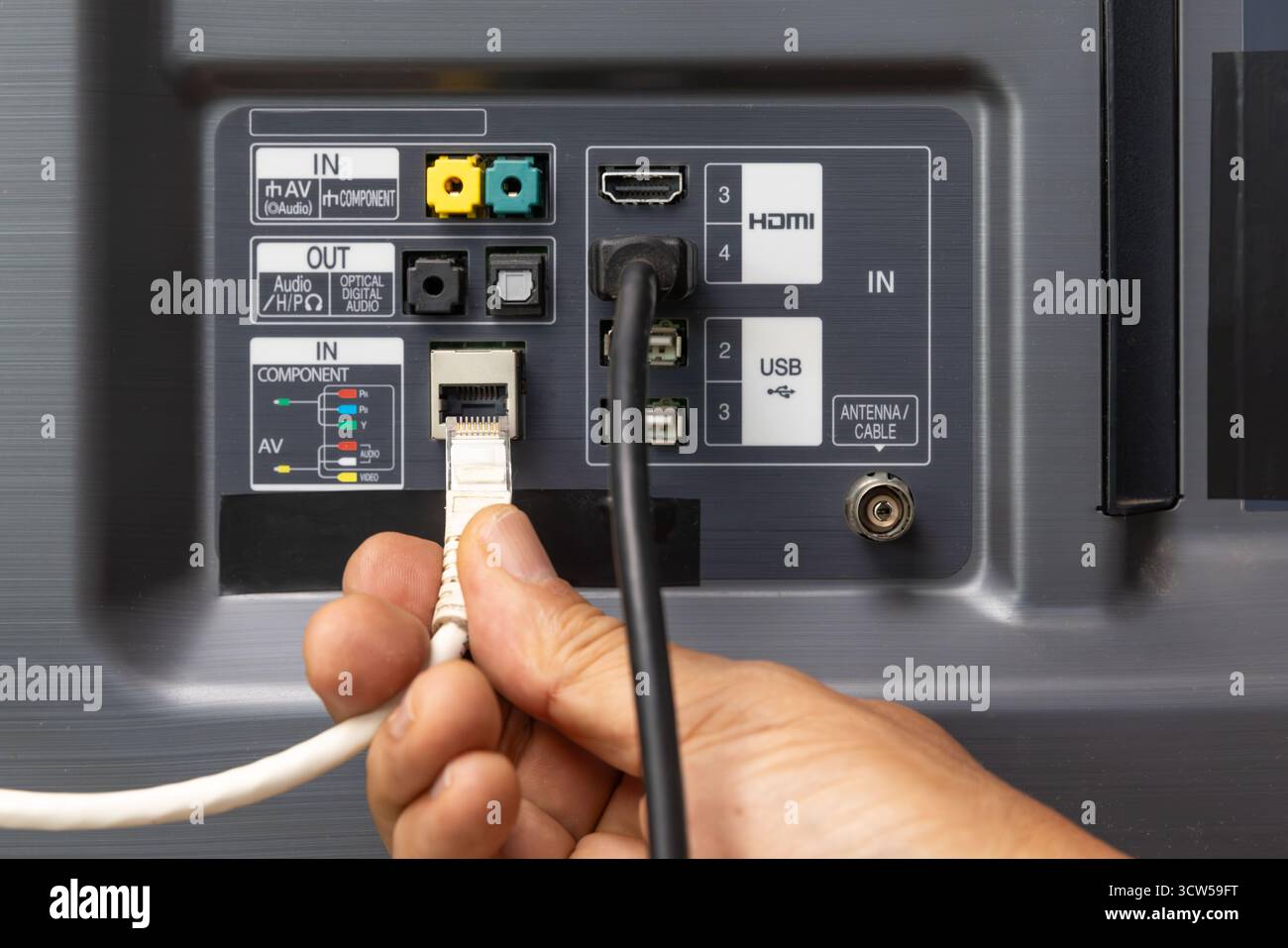 Man connecte le câble Internet au téléviseur. Banque D'Images