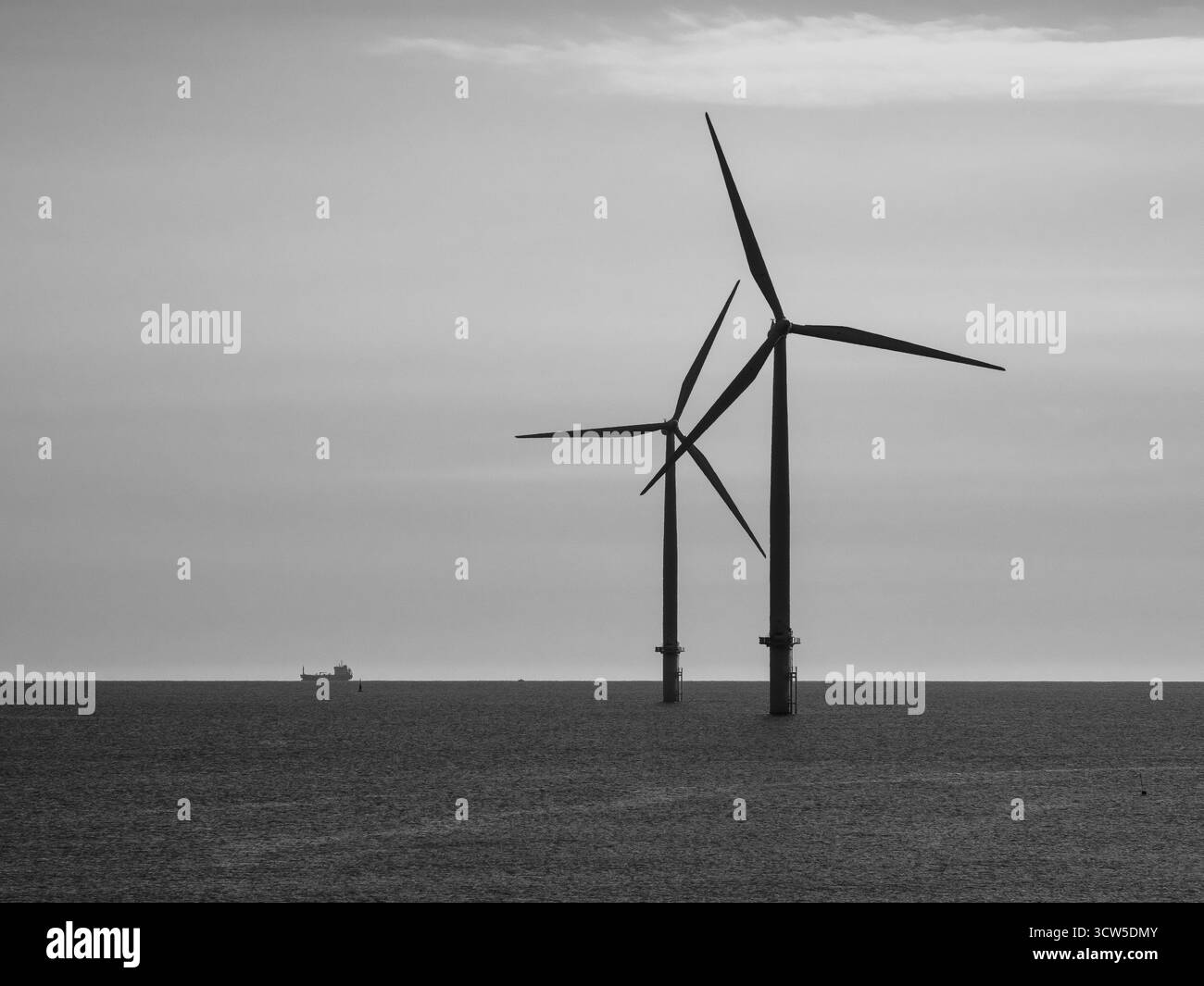 Éoliennes offshore et cargo lointain en noir et blanc Banque D'Images