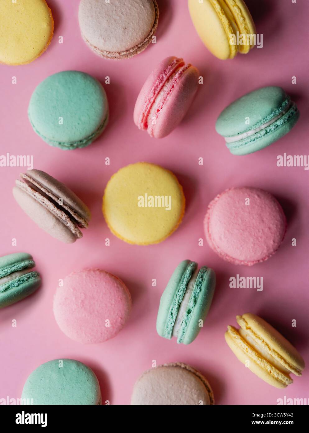 Vue de dessus gros plan de macarons colorés sur fond rose. Banque D'Images