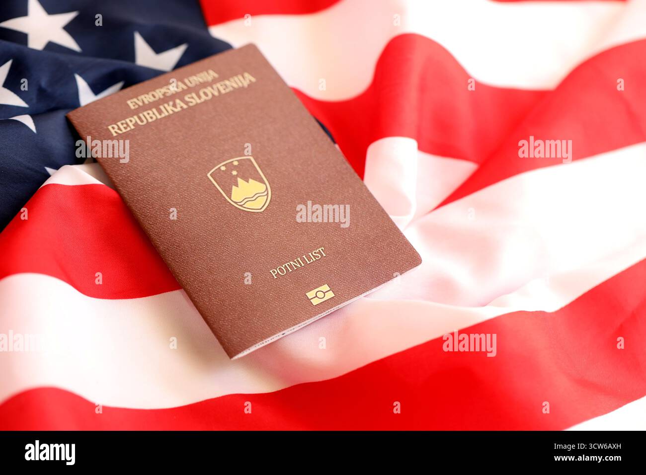 Passeport slovène sur grand drapeau agitant des États-Unis d'Amérique close up. Visa AMÉRICAIN et concept d'immigration Banque D'Images