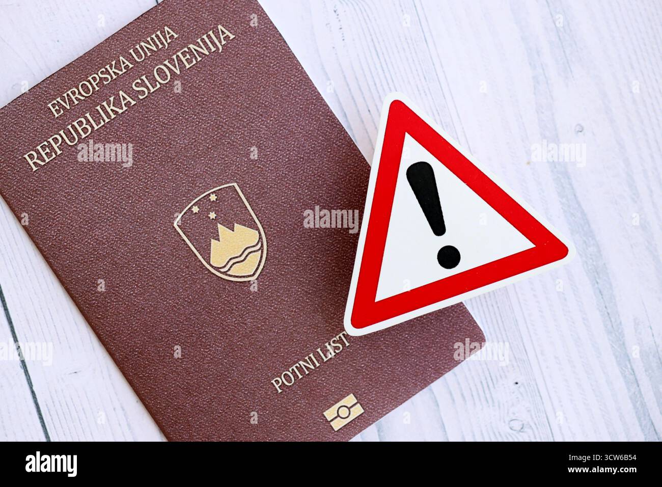 Passeport slovène avec signe d'exclamation sur fond en bois blanc gros plan. Problèmes de citoyenneté en Europe concept Banque D'Images