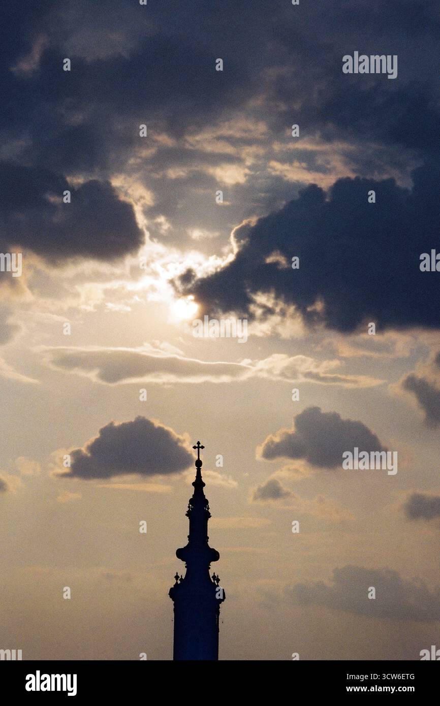 Nuages sombres au-dessus de la tour silhouette de la cathédrale orthodoxe de Novi Sad. La lumière se brise derrière. Tension et immobilité dans un seul cadre. Banque D'Images
