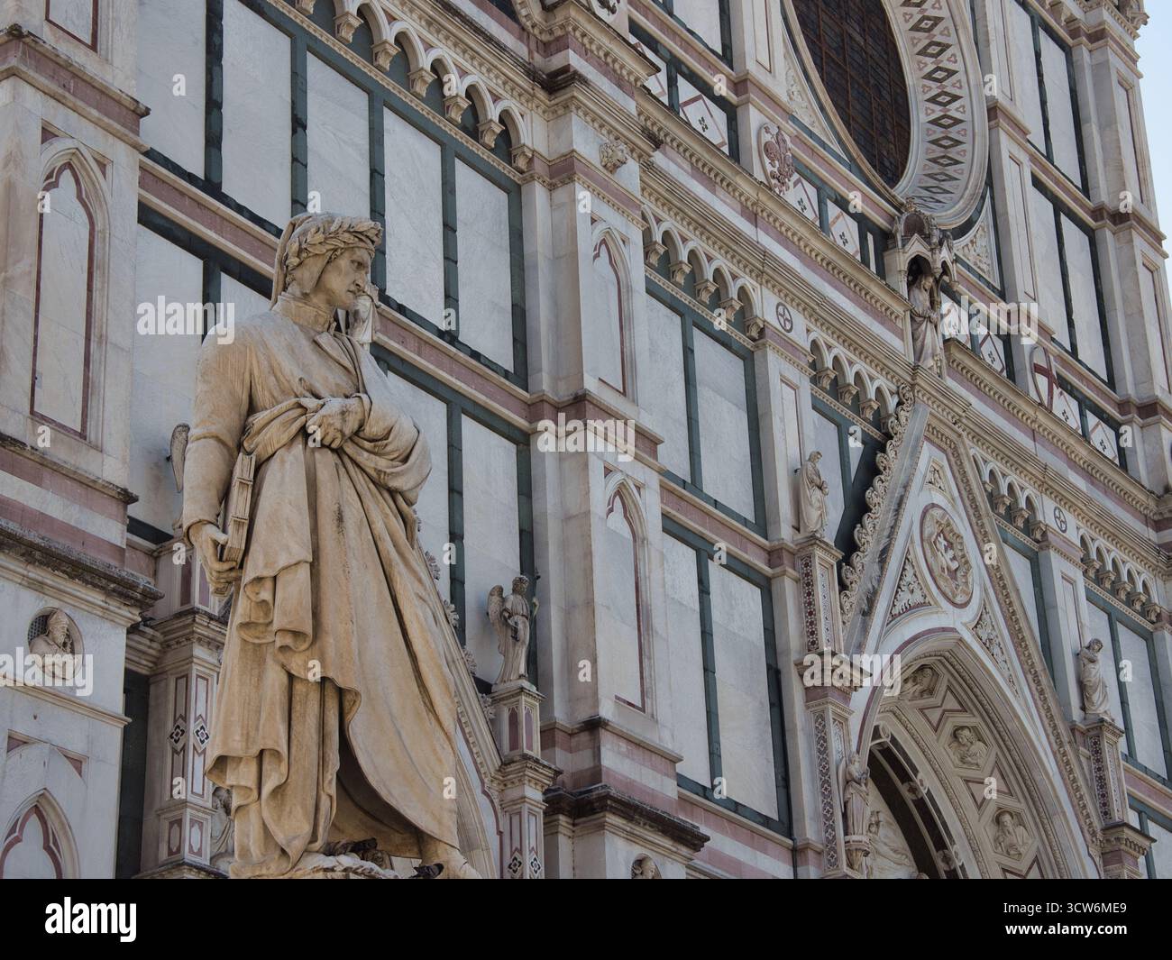 Statue de Dante Alighieri contre la façade de Santa Croce - Un gros plan de la statue du poète italien Dante Alighieri contre le blanc et vert à motifs mar Banque D'Images