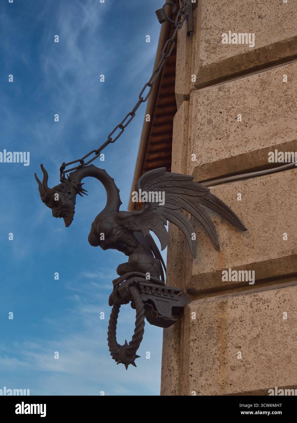 Anneau d'attelage du dragon de fer forgé sur le mur de pierre - gros plan d'un dragon mythique en fer forgé élaboré et menaçant avec des ailes, enchaîné à un palais de pierre Banque D'Images