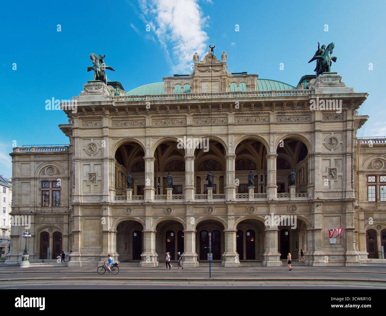 Façade de l'Opéra national de Vienne - extérieur néo-Renaissance du célèbre Wiener Staatsoper en Autriche par une journée d'été lumineuse avec des gens qui passent. Banque D'Images