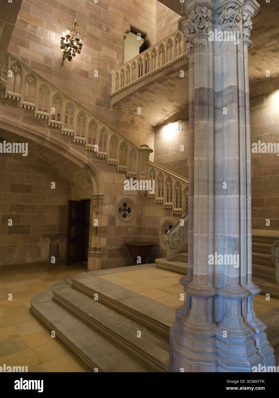 Imposant escalier et colonne du palais néo-gothique - vue intérieure d'un large escalier en pierre, d'une balustrade ornée et d'une colonne sculptée massive à Sobrellan Banque D'Images