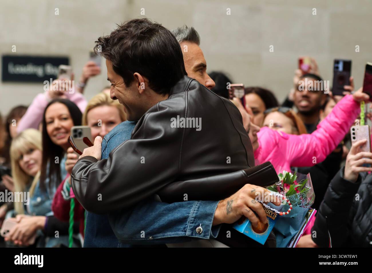 Londres, Royaume-Uni, 10 octobre 2025. Robbie Williams quitte la BBC après être apparu sur BBC Radio 1 Live Lounge. Il embrasse Mark Ronson qui est sorti de la BBC pour le voir. Crédit : Ben Shaw/Alamy Live News Banque D'Images