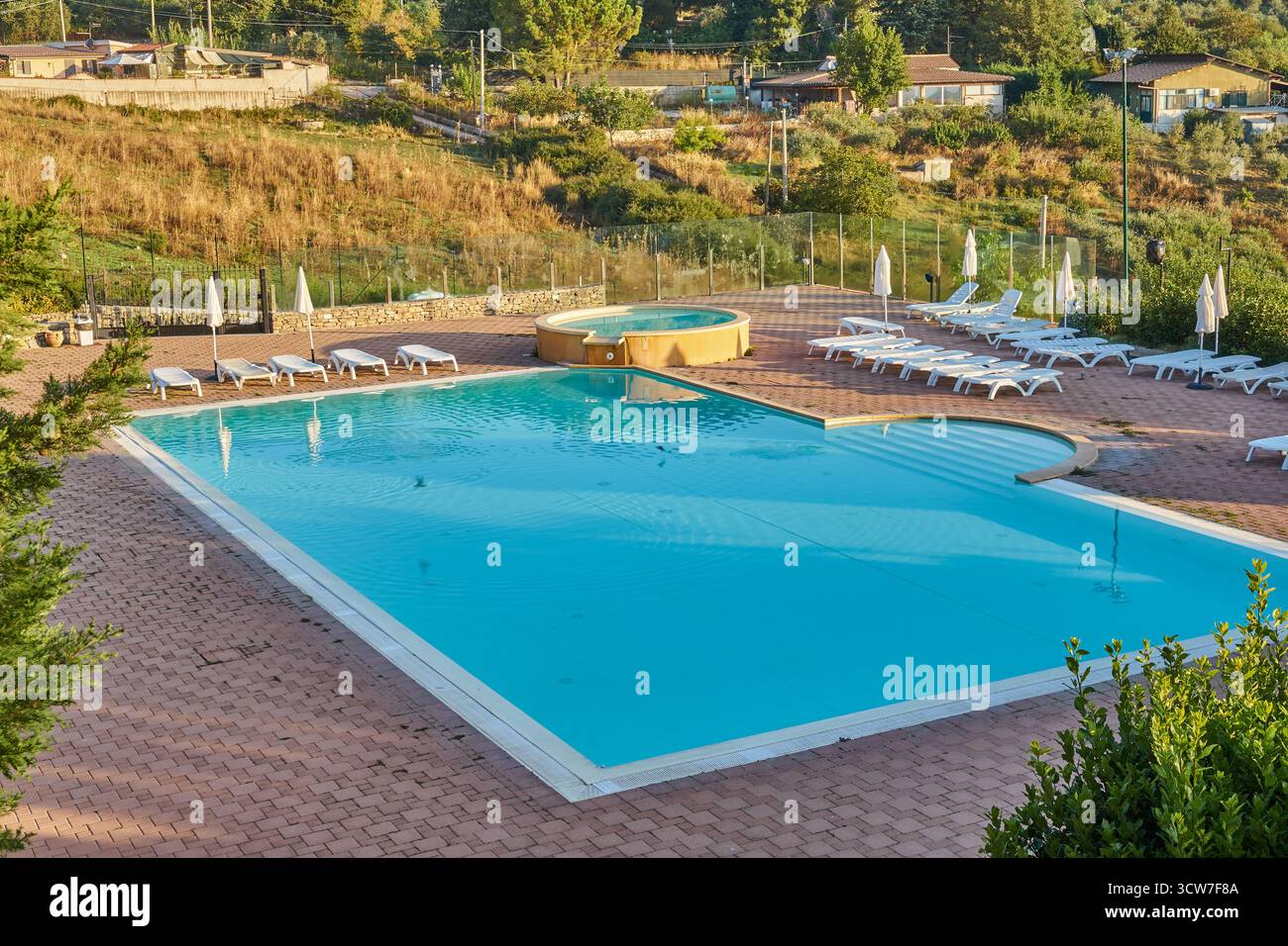 Terrasse tranquille de la piscine à flanc de colline avec eau turquoise et vue panoramique sur la campagne dans le matin Piana degli Albanesi, Italie Banque D'Images