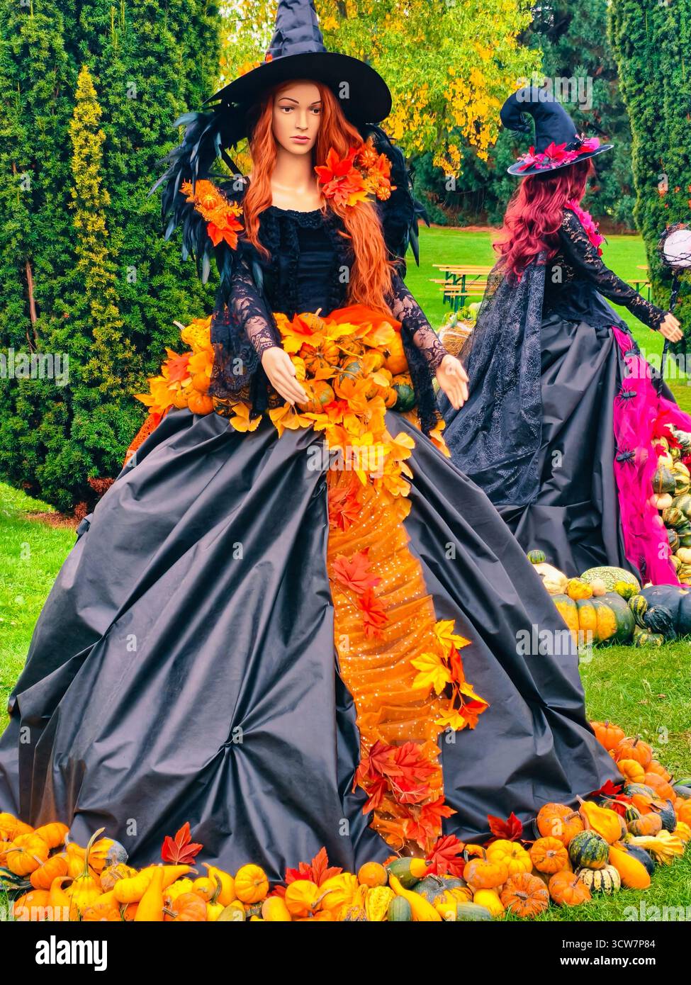 Halloween Witch costume femme en robe noire avec citrouilles Fall Leaves Autumn Garden Party décoration Fantasy personnage Portrait. Arrière-plan de la nature Banque D'Images