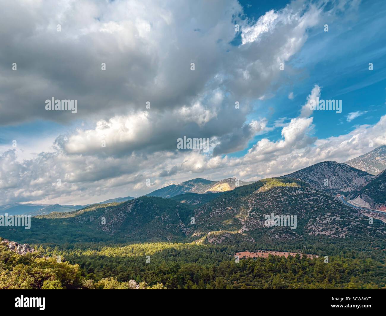 Large vue sur la vallée sous ciel nuageux avec des crêtes de montagne et des forêts Banque D'Images