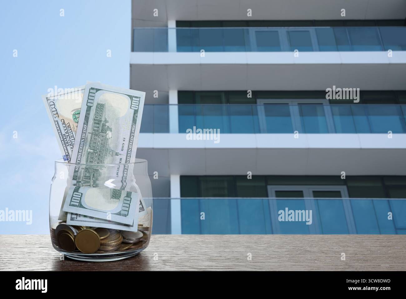 Pot avec des dollars et des pièces contre condominium. Économiser de l'argent pour acheter appartement Banque D'Images