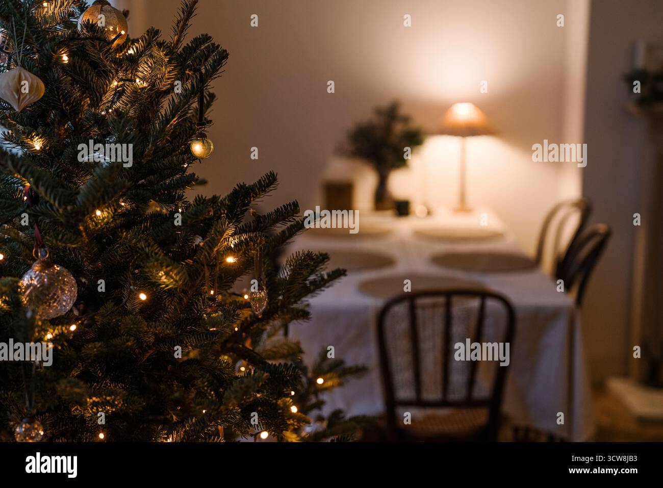 Sapin de Noël minimaliste avec des ornements dorés et des lumières fées chaudes dans un cadre confortable de salle à manger. Banque D'Images