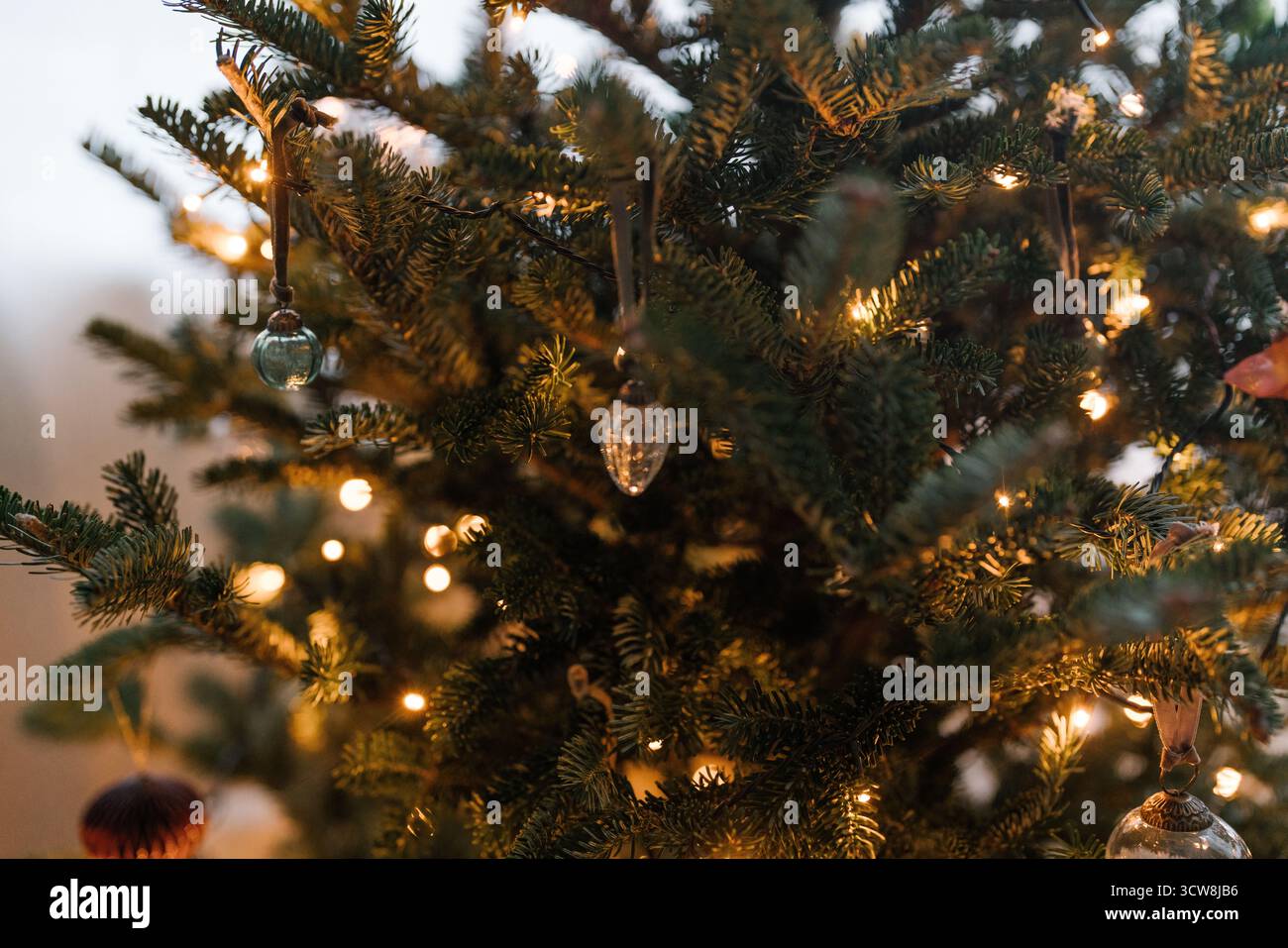 Gros plan d'un sapin de Noël minimaliste esthétique avec des boules et des lumières de fée chaudes, esprit festif, vacances d'hiver confortables. Tons chauds et confort Banque D'Images